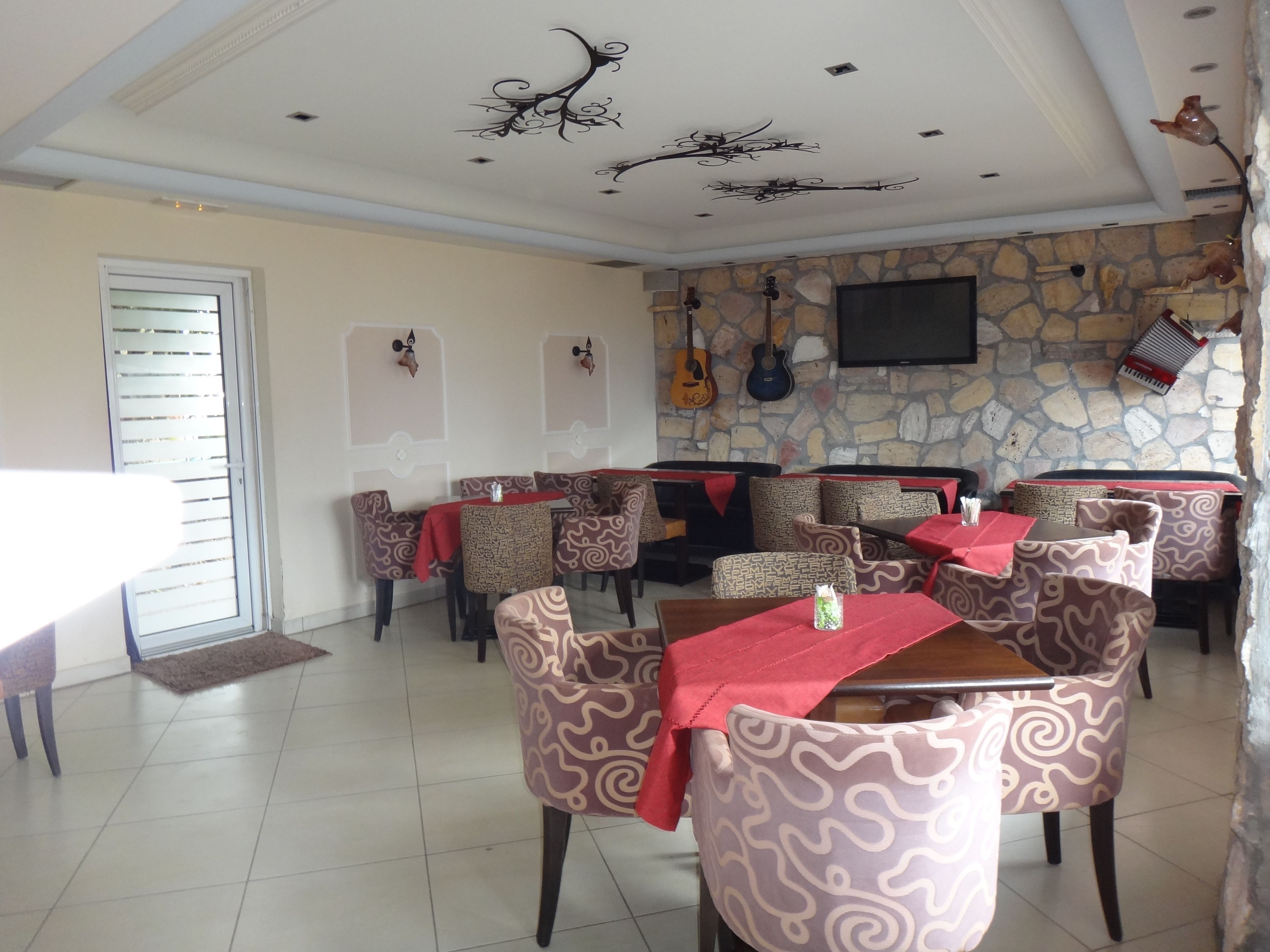 Un restaurante con sillas y mesas estampadas, una pared de piedra y un televisor de pantalla plana.