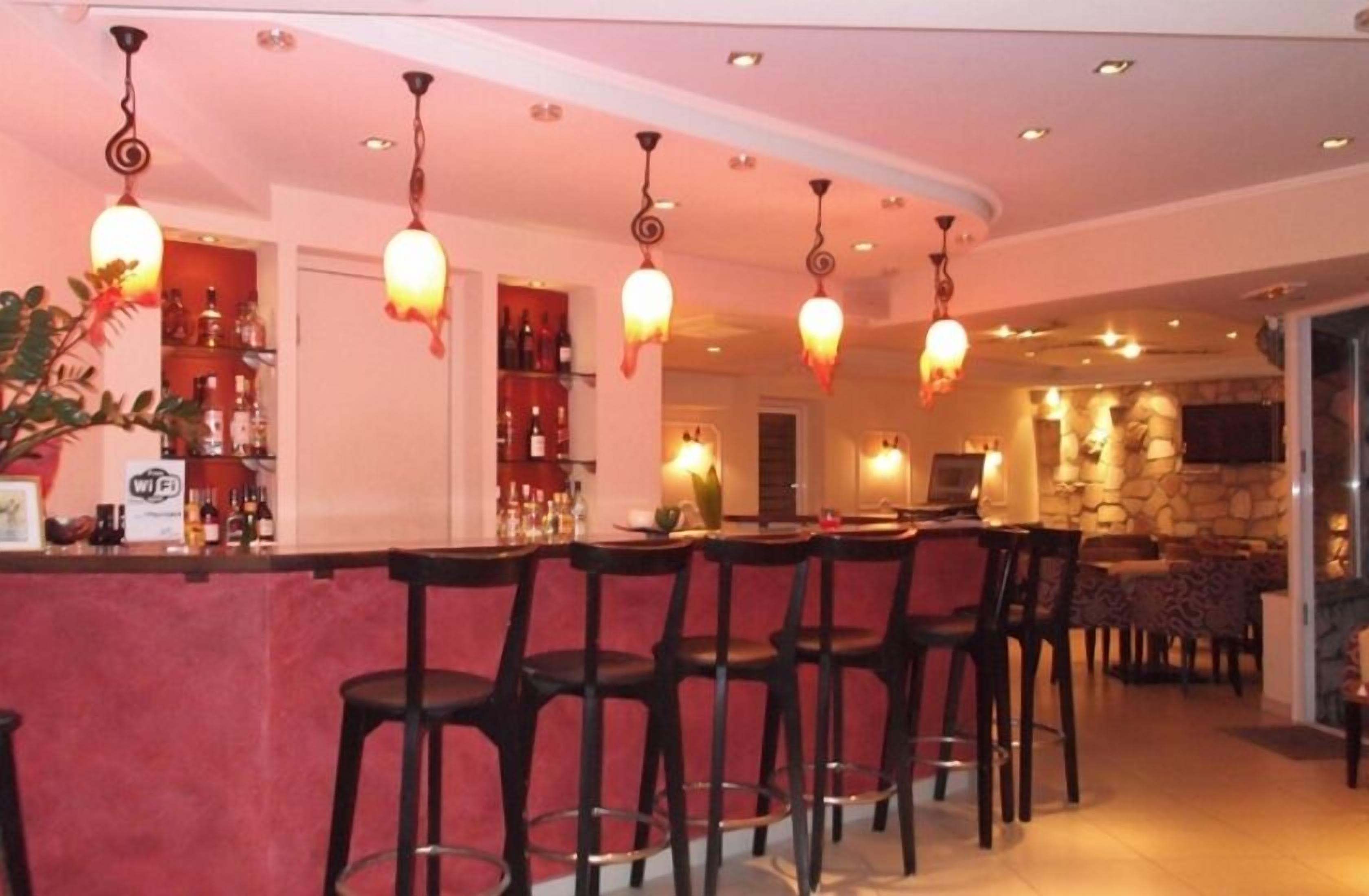 A bar area with multiple stools, a counter with a WiFi sign, and a stone wall in the background.