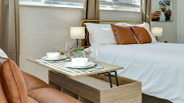 A neatly arranged hotel room with a bed, bedside table, and a small dining area. - Dream Inn Hotel (Hollywood)