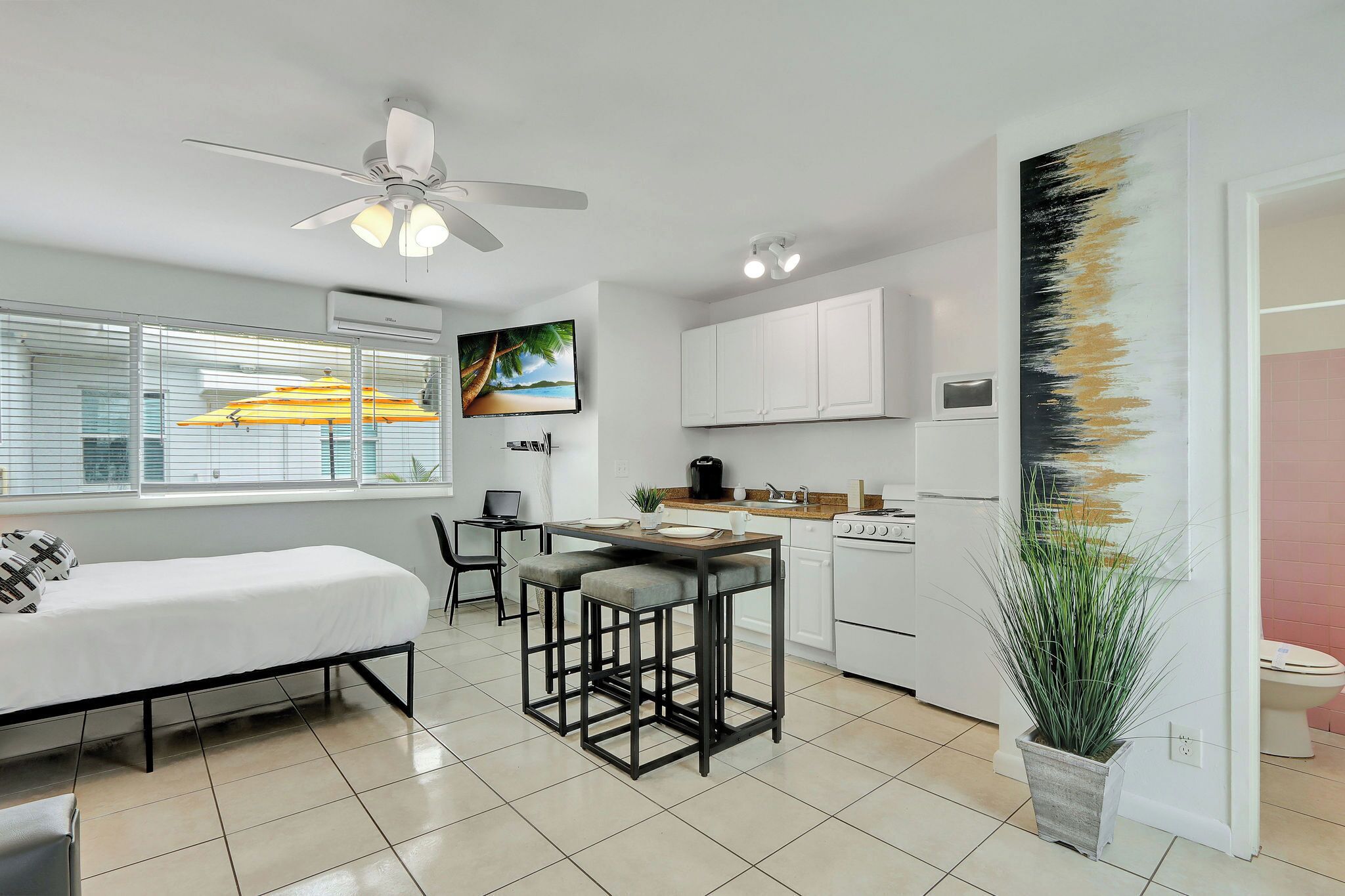 A modern kitchen with white cabinets, a dining area with a table and chairs, and a ceiling fan.