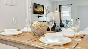 A dining table set with white plates, bowls, and wine glasses, with a woven basket and a bowl of fruit. - Dream Inn Hotel (Hollywood)