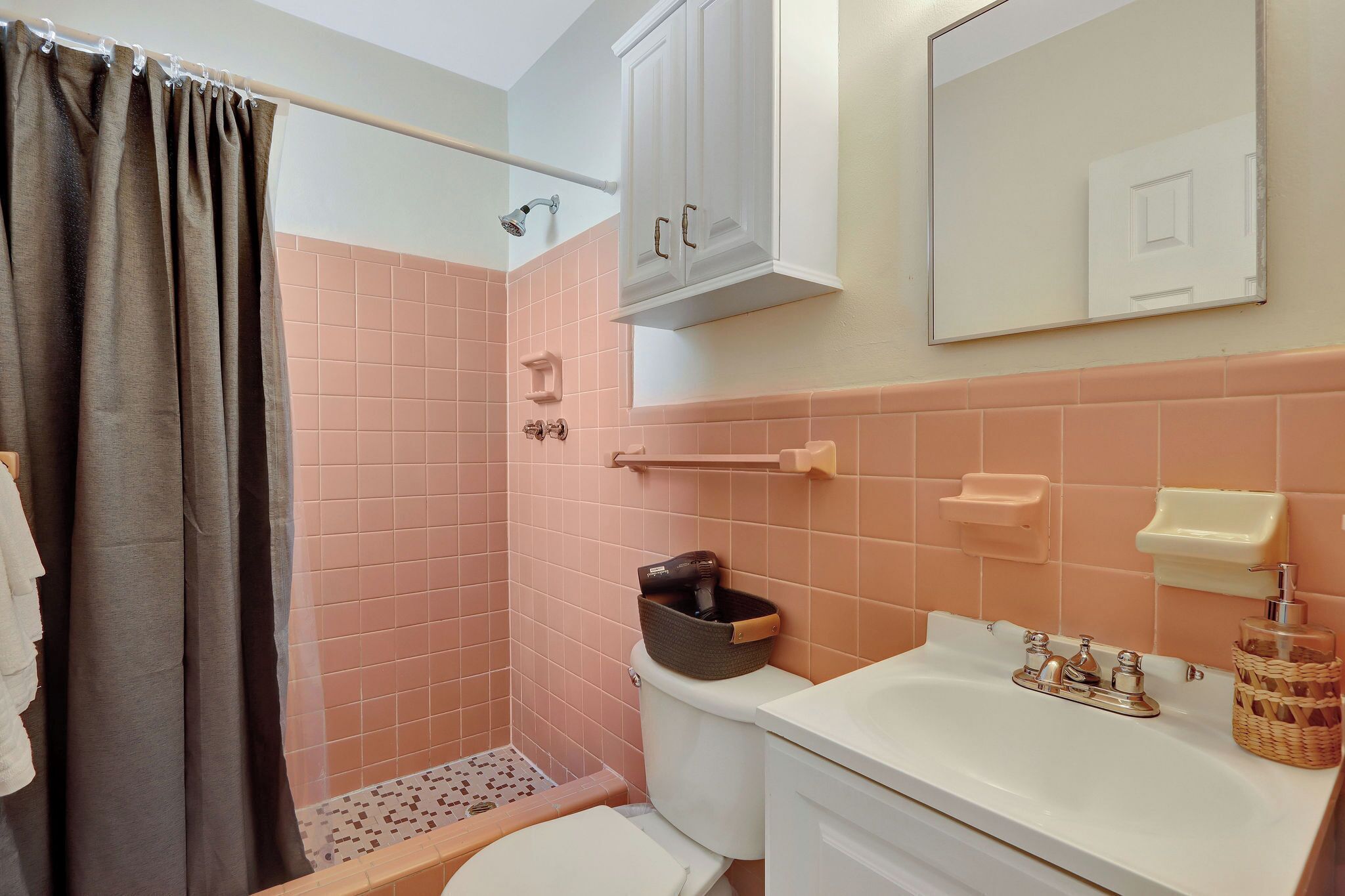 A bathroom with a shower, toilet, sink, and cabinet.