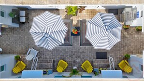 A rooftop terrace with two large striped umbrellas, yellow lounge chairs, and a pool area. - Dream Inn Hotel (Hollywood)