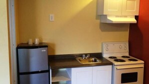 A compact kitchen with a refrigerator, stove, and sink. - Parkway Motel (London)