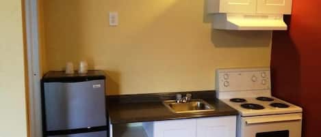 A compact kitchen with a refrigerator, stove, and sink.