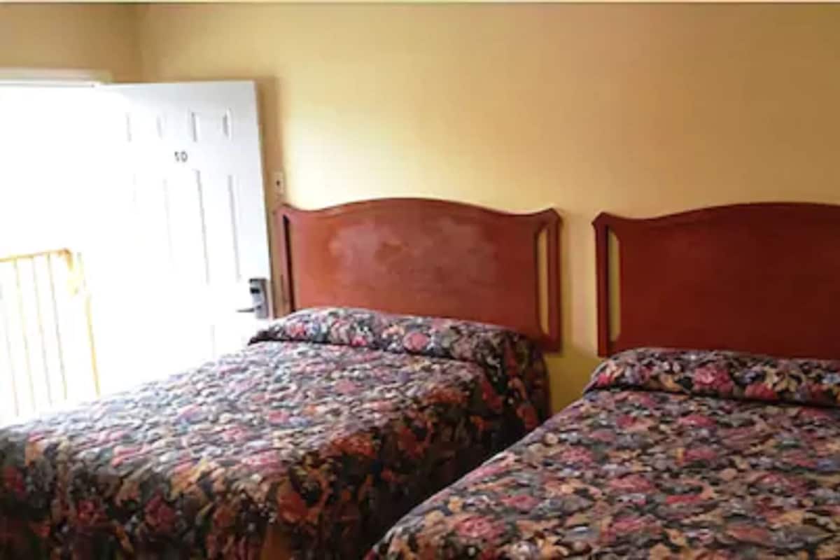 Two single beds with floral bedding in a room with yellow walls and a white door.