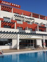 A hotel with a pool, outdoor seating, and a sign indicating three stars.