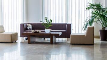 A modern living room with a sofa, two armchairs, a coffee table, and two potted plants.