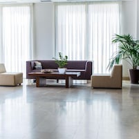 Uma sala de estar moderna com um sofá, duas poltronas, uma mesa de centro e duas plantas em vasos.