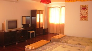 A hotel room with a television, a desk, a chair, a bed, and a window with curtains. - Himalaya Residence (Bangkok)
