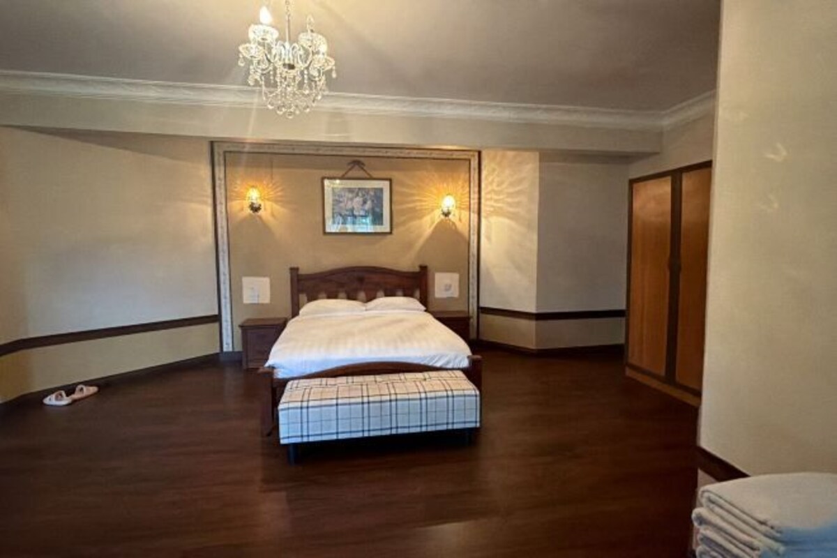 Camera da letto con un letto di legno, una panca, un lampadario e due luci a parete.