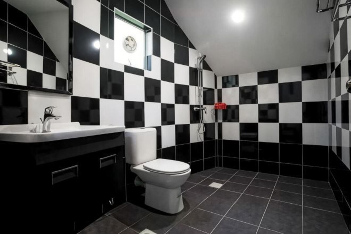 Un bagno con pavimento a scacchi bianchi e neri, un water bianco e un lavandino con uno specchio sopra.