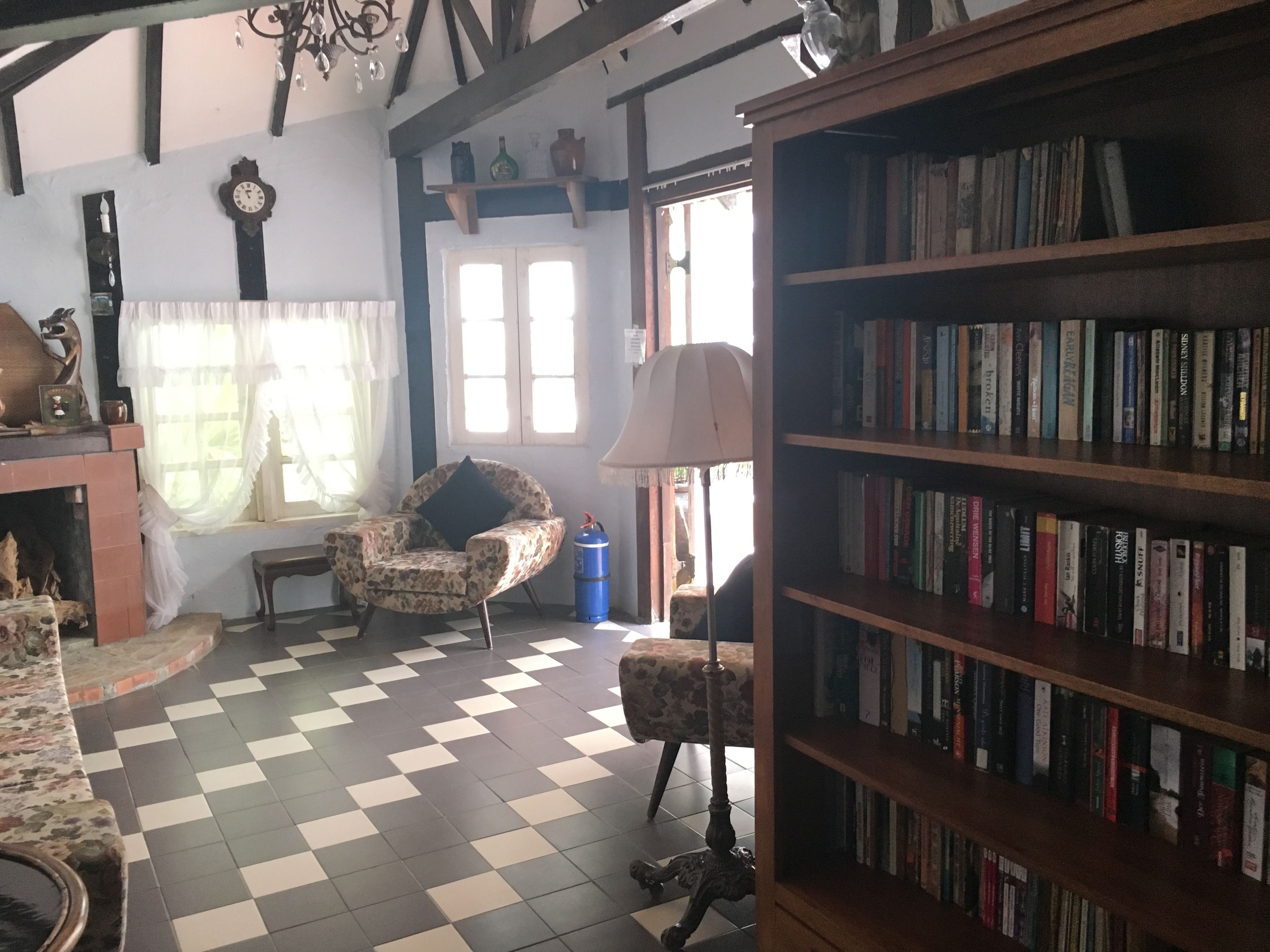 A cozy room with a checkered floor, a bookshelf filled with books, a fireplace, and a chair.