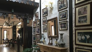 A hallway with a dining area, a fireplace with framed photos, and a clock. - The Bala's Holiday Chalet (Tanah Rata)