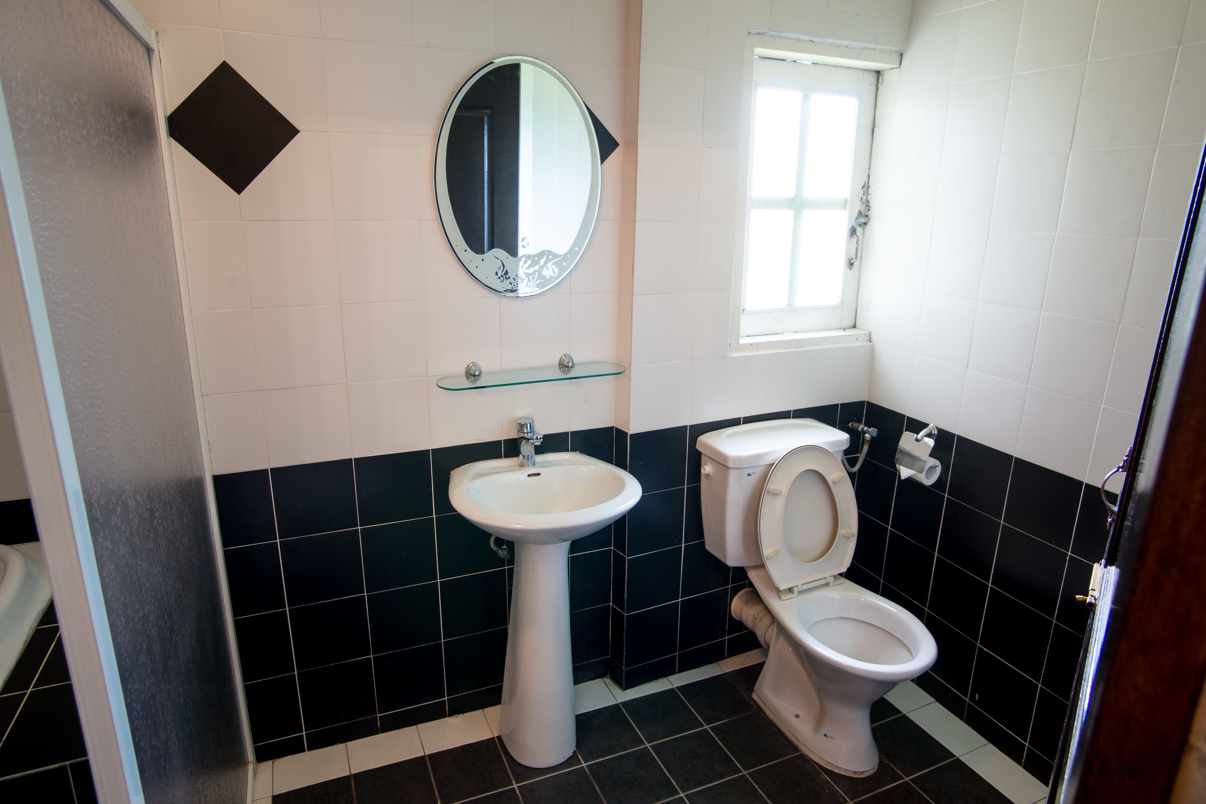 Un bagno con lavandino bianco, un water, uno specchio e una finestra.