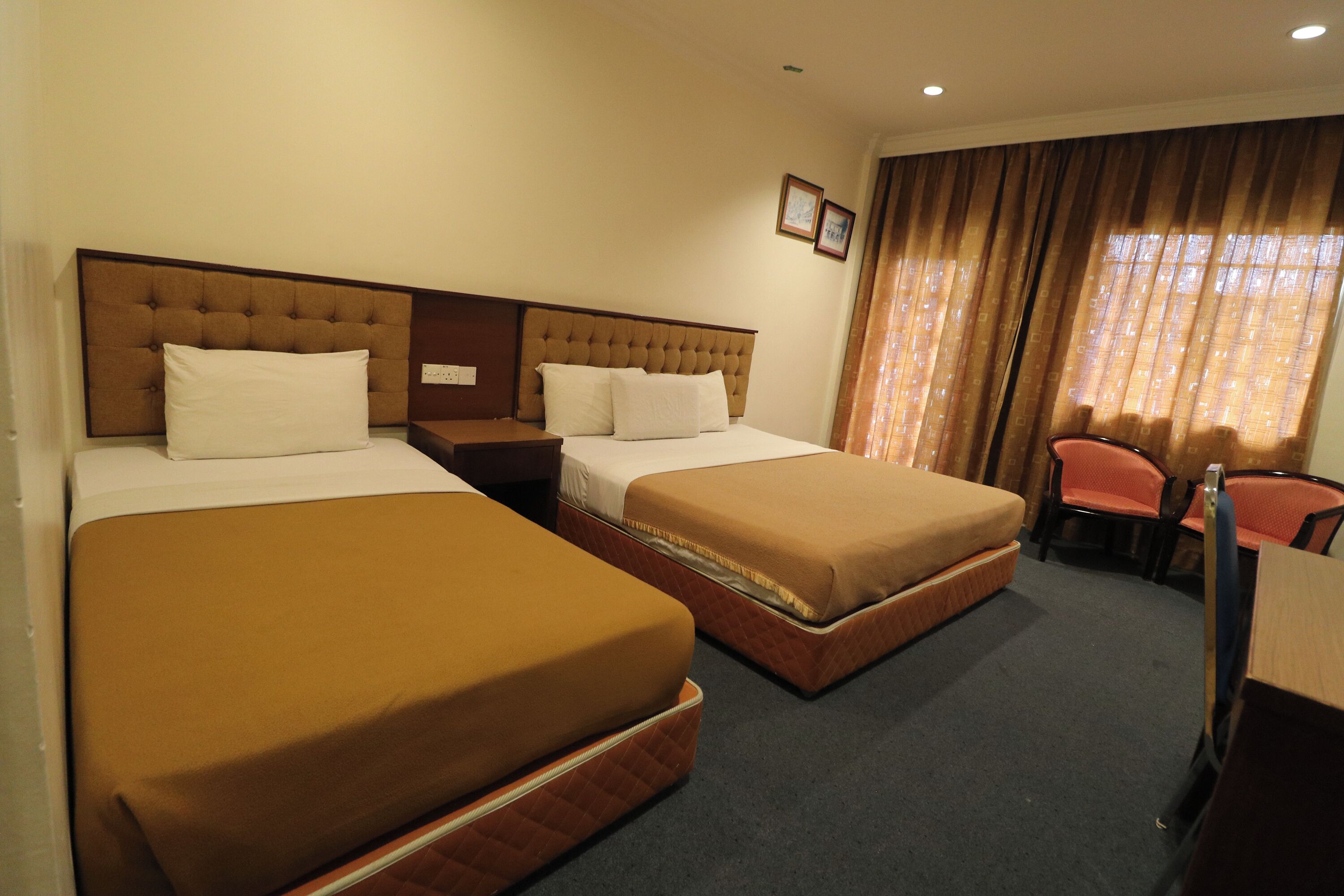 A hotel room with two beds, a desk, and a chair.