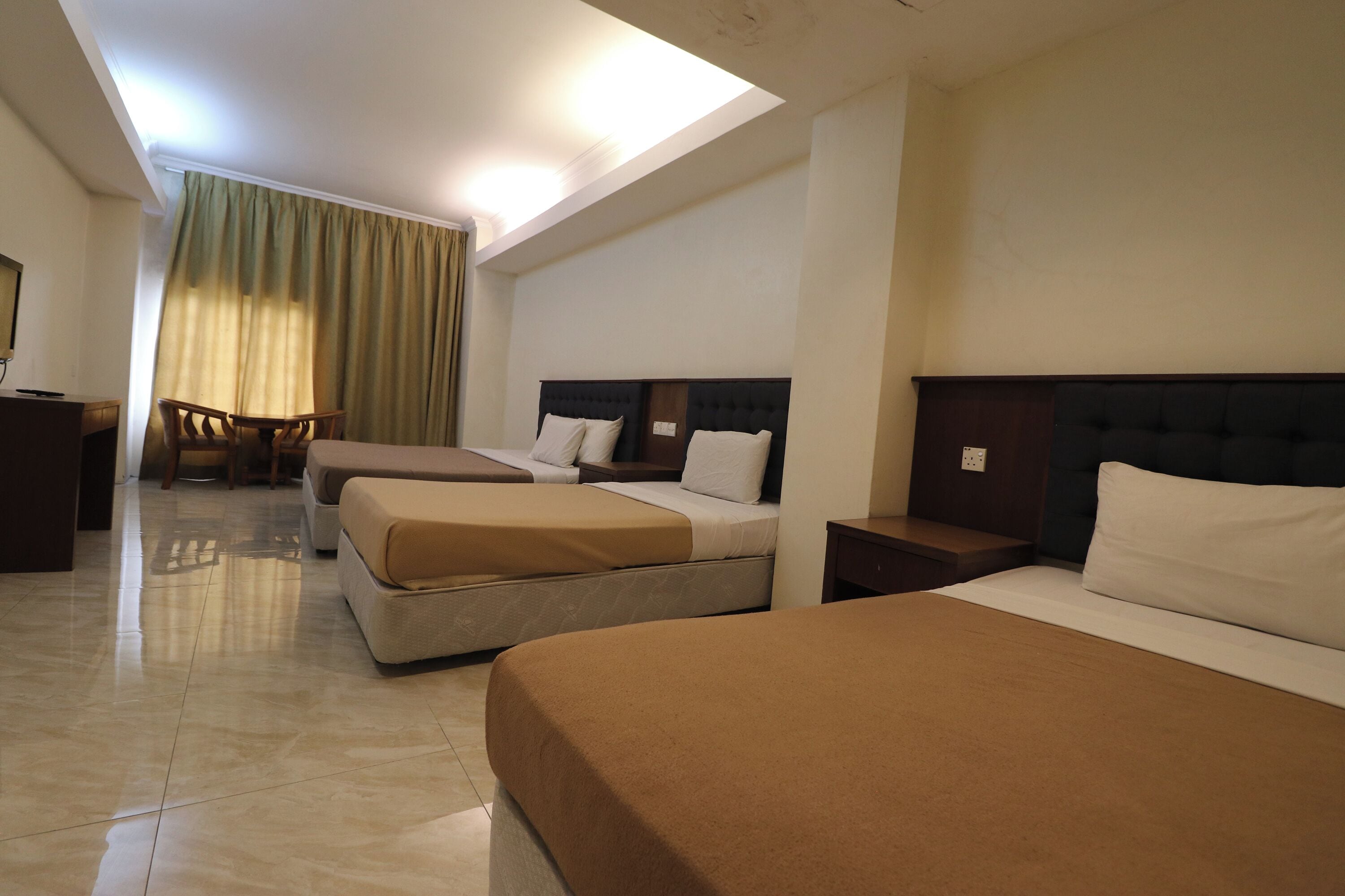 Une chambre d’hôtel avec trois lits, un bureau et une chaise.