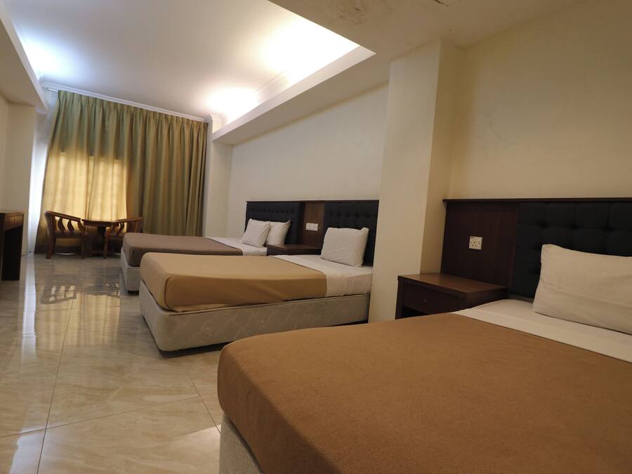 Habitación de hotel con tres camas, un escritorio y una silla.