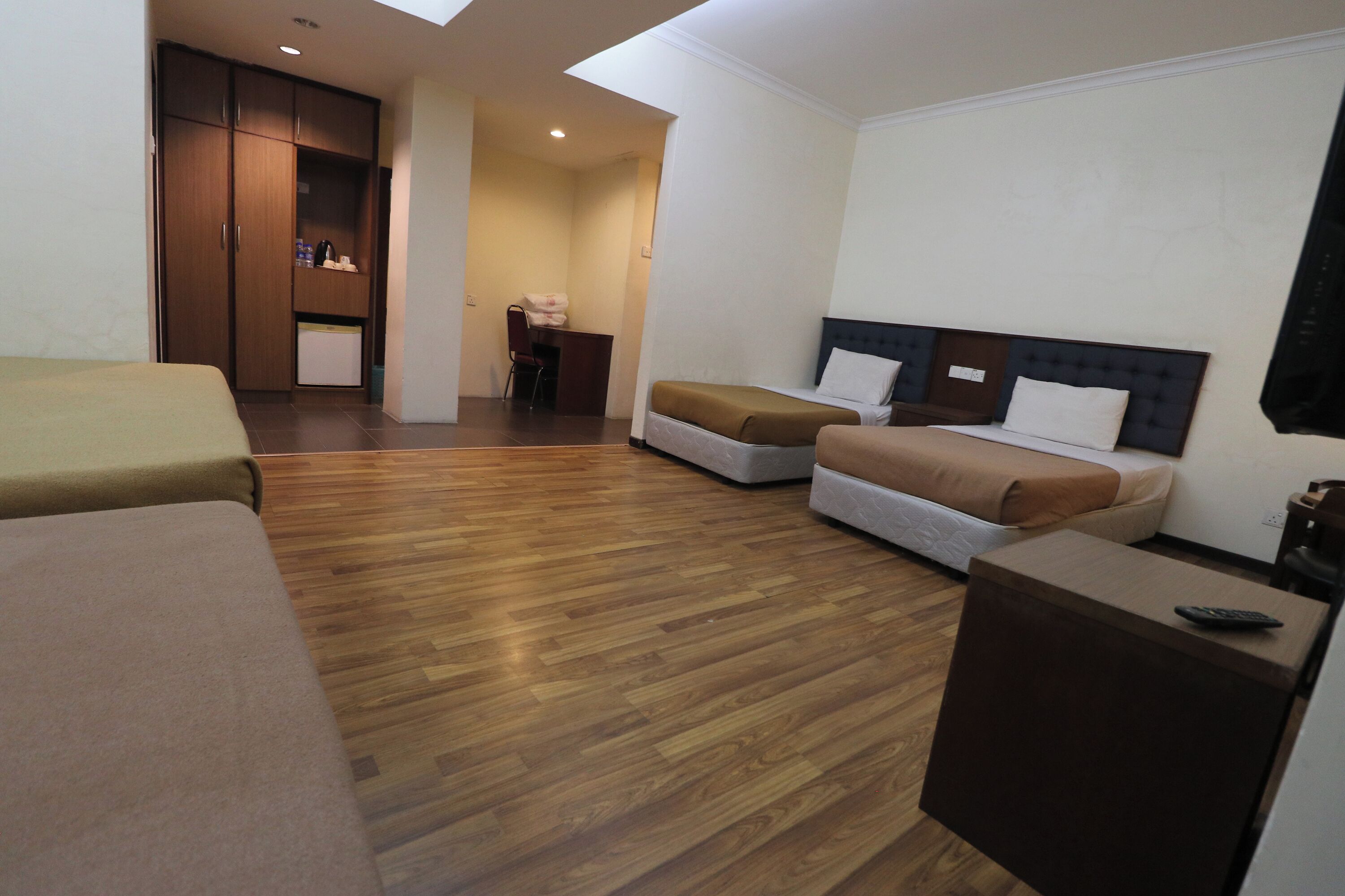 A hotel room with two beds, a desk, and a wardrobe.