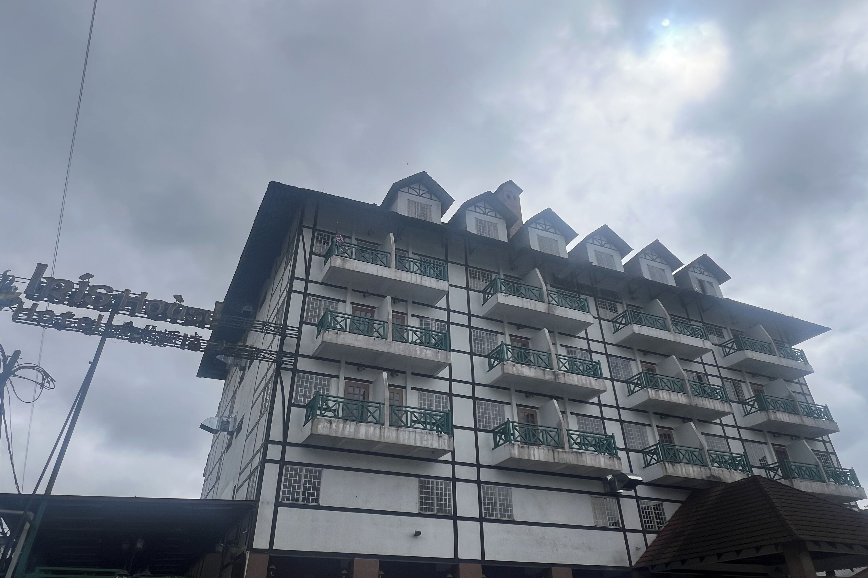 A multi-story building with balconies and a sign indicating it is a hotel.