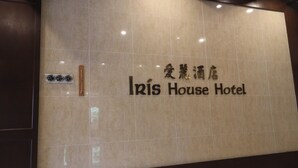 A sign for Iris House Hotel with a marble wall background and a ruler for scale.