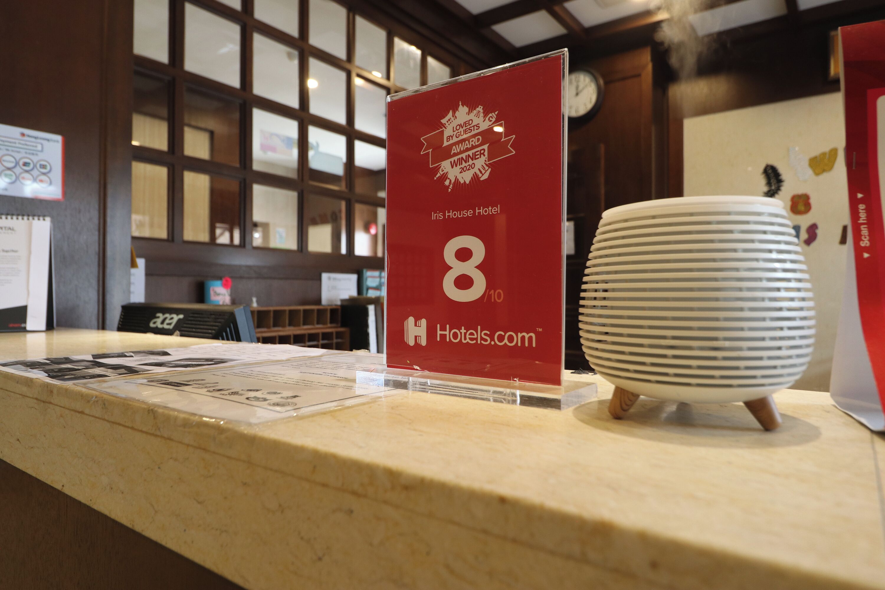 A hotel reception desk with a red award sign, a white paperweight, and a clock on the wall.