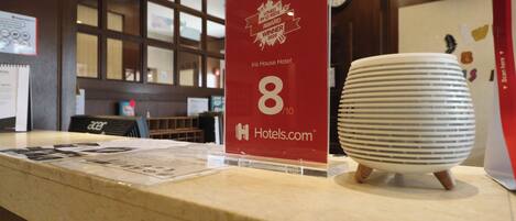 A hotel reception desk with a red award sign, a white paperweight, and a clock on the wall.