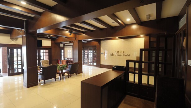 A hotel lobby with a reception desk, seating area, and a large window.
