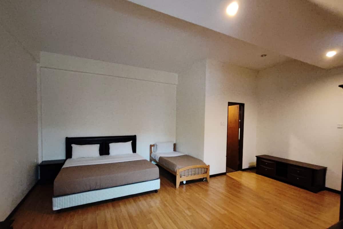 A bedroom with a large bed, a smaller bed, a bench, and a dresser.