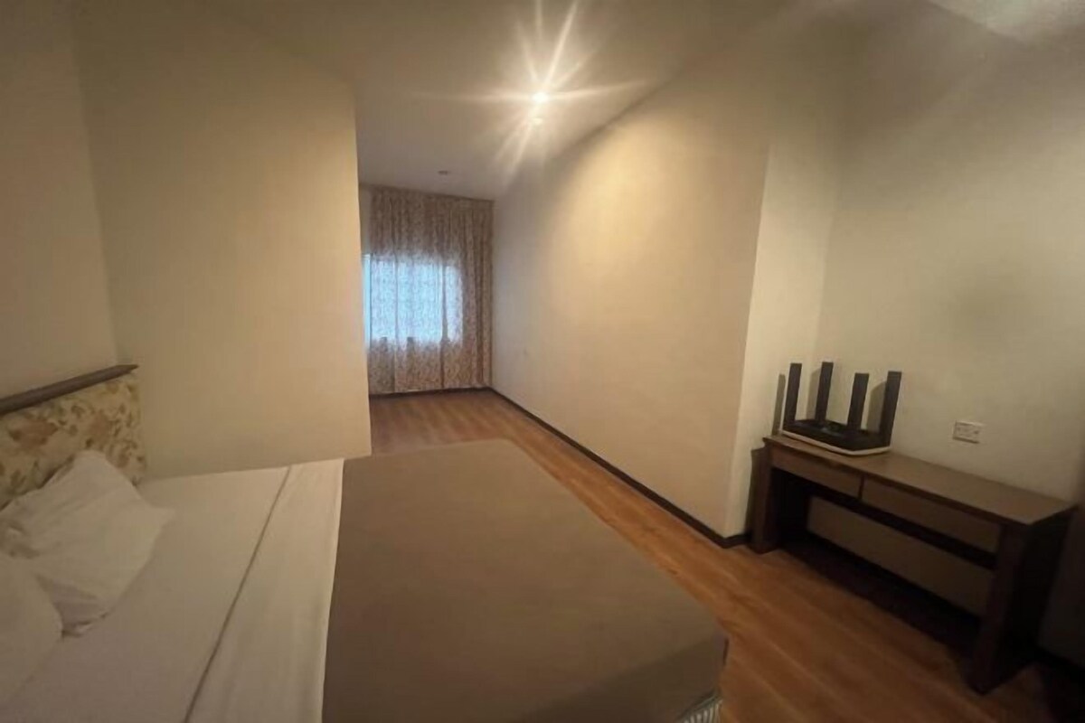 A bedroom with a bed, a desk, and a window with curtains.