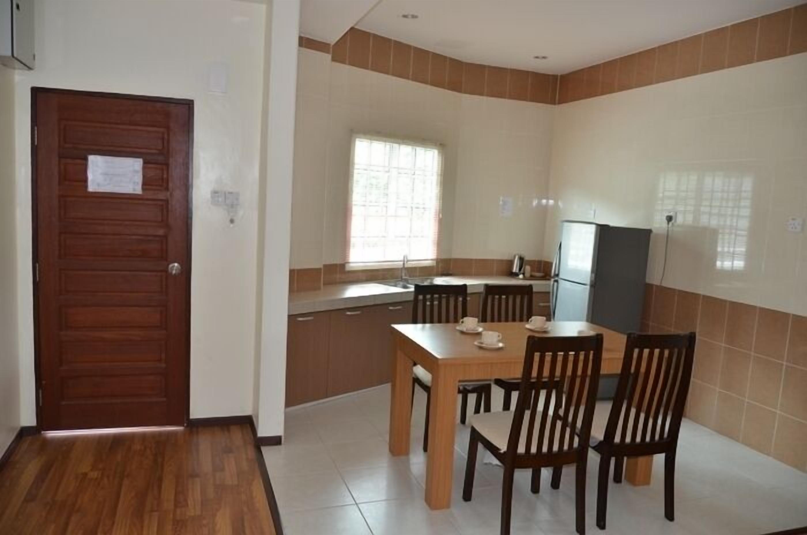 A compact kitchen with a dining area, wooden door, and tiled walls.