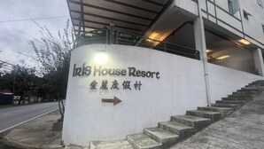 Een bordje van Iris House Resort met een trap die naar de ingang leidt.