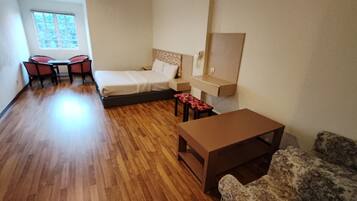 Una habitación compacta con cama, una mesita, sofá, escritorio y silla.
