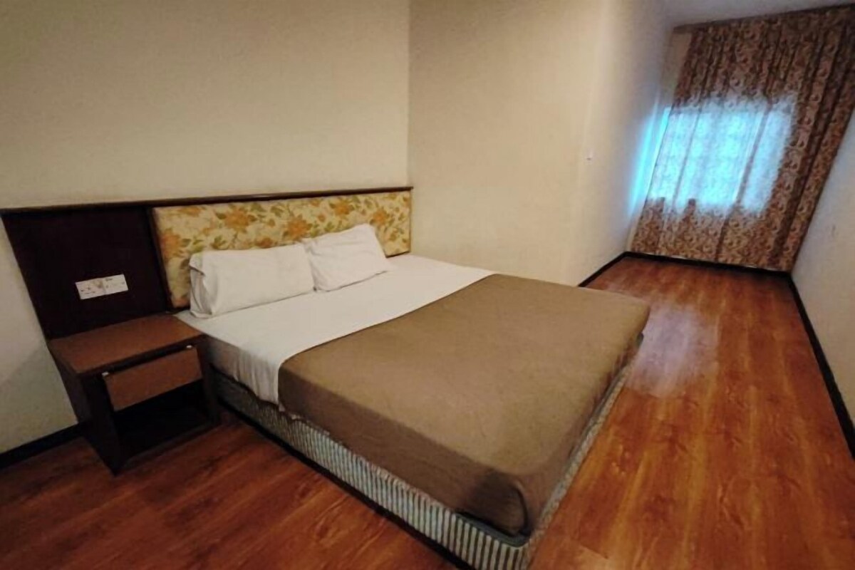 A single bed with a headboard, a nightstand, and a window with curtains.