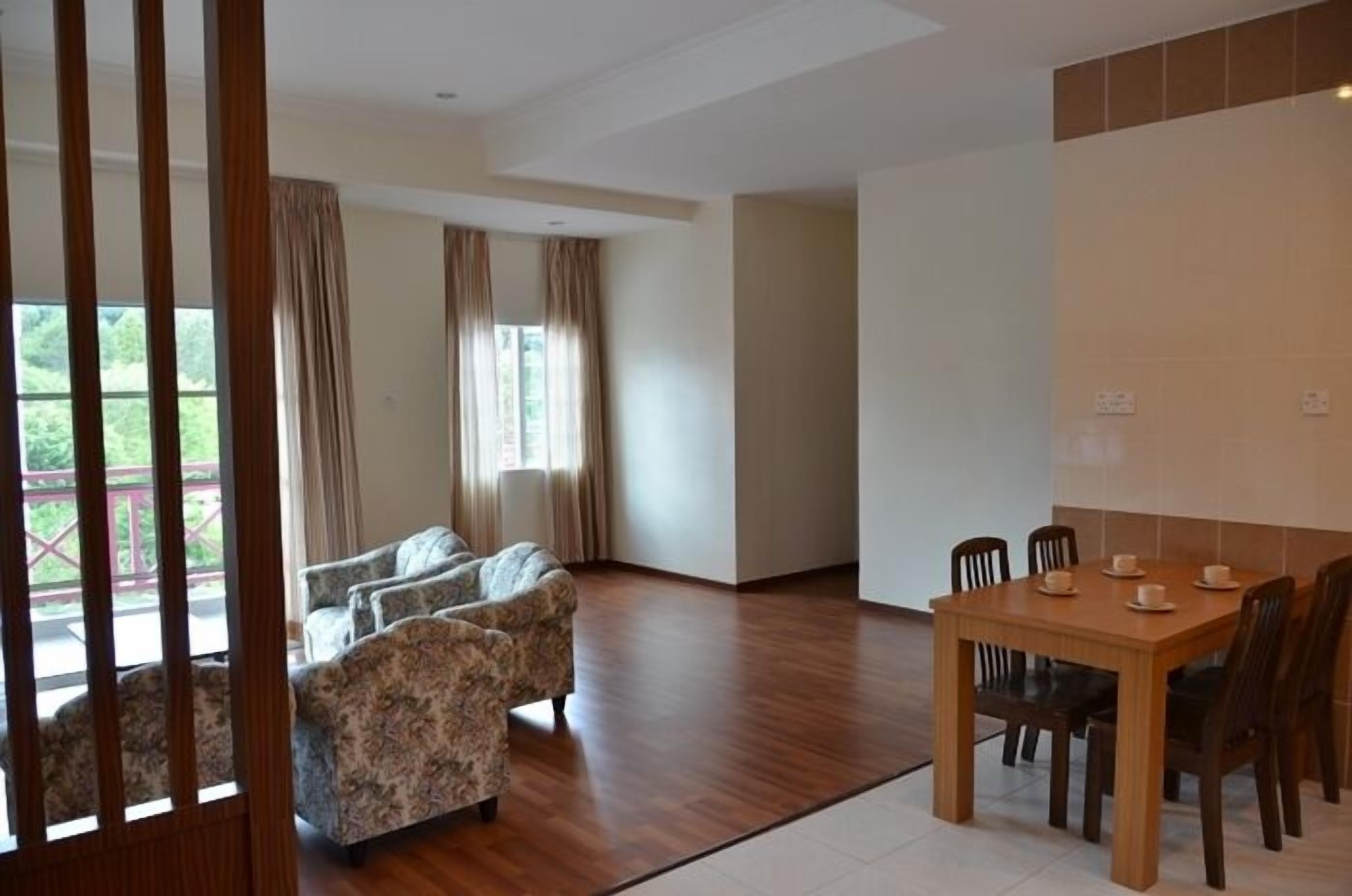 Una habitación amplia con suelo de madera, una mesa de comedor con sillas y un conjunto de sofá.