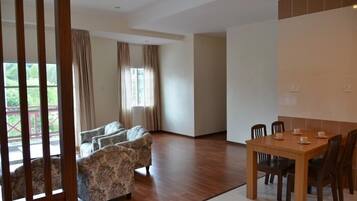 Una habitación amplia con suelo de madera, una mesa de comedor con sillas y un conjunto de sofá.