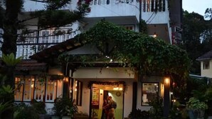 A building with a covered entrance, potted plants, and a person standing at the door. - Hillview Inn (Tanah Rata)