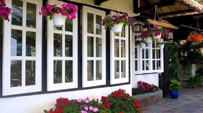 Un edificio con ventanas de marco blanco, cestas de flores colgantes y plantas en macetas.