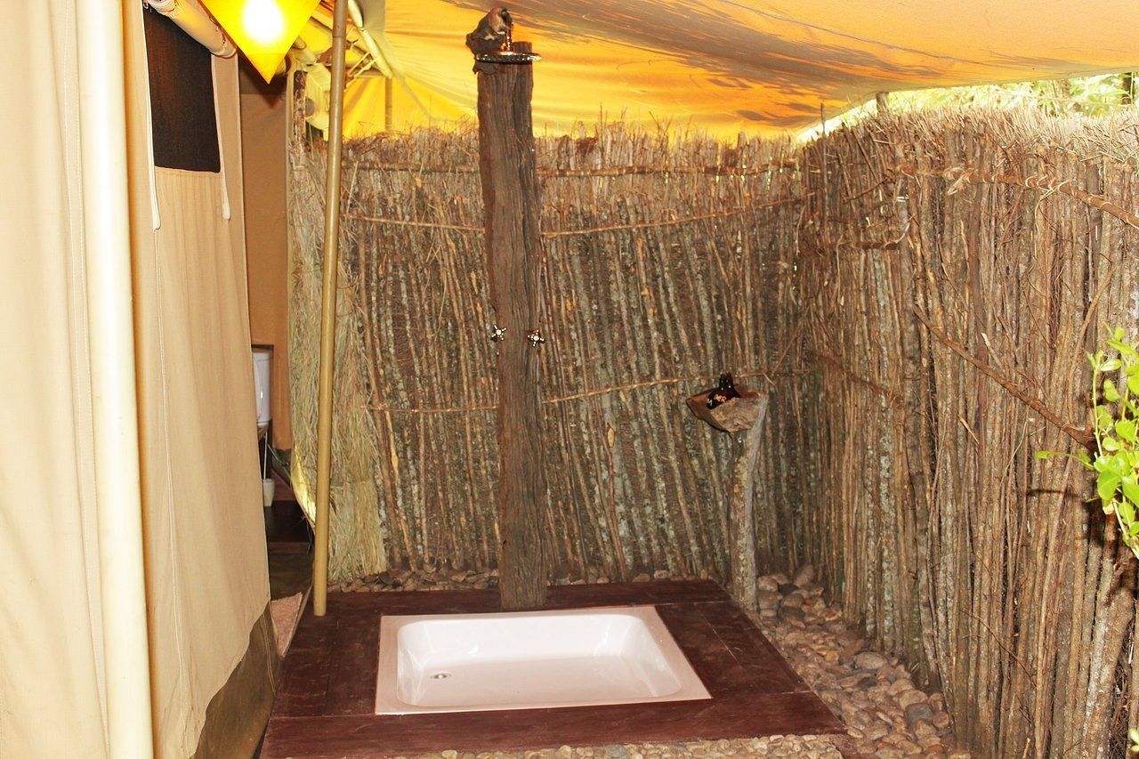 A small, enclosed shower area with a wooden post and a hanging light fixture.