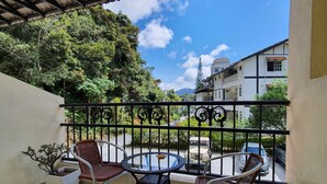 A balcony with a view of a street, a table, chairs, and a potted plant. - Arundina Cameron Highlands (Tanah Rata)