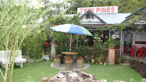 Un jardín con una fogata, asientos al aire libre y un letrero que dice 'Twin Pines'.