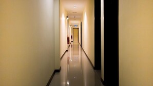 A long, narrow hallway with a reflective floor, leading to a door at the end. - 118 Hotel (George Town)