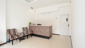 A reception area with a reception desk, two striped chairs, and a small table. - 118 Hotel (George Town)