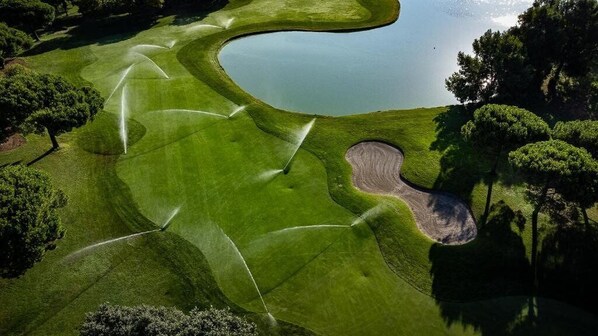 A golf course with a water hazard, sand bunkers, and trees. - Hotel Golf Inn (Lignano Sabbiadoro)