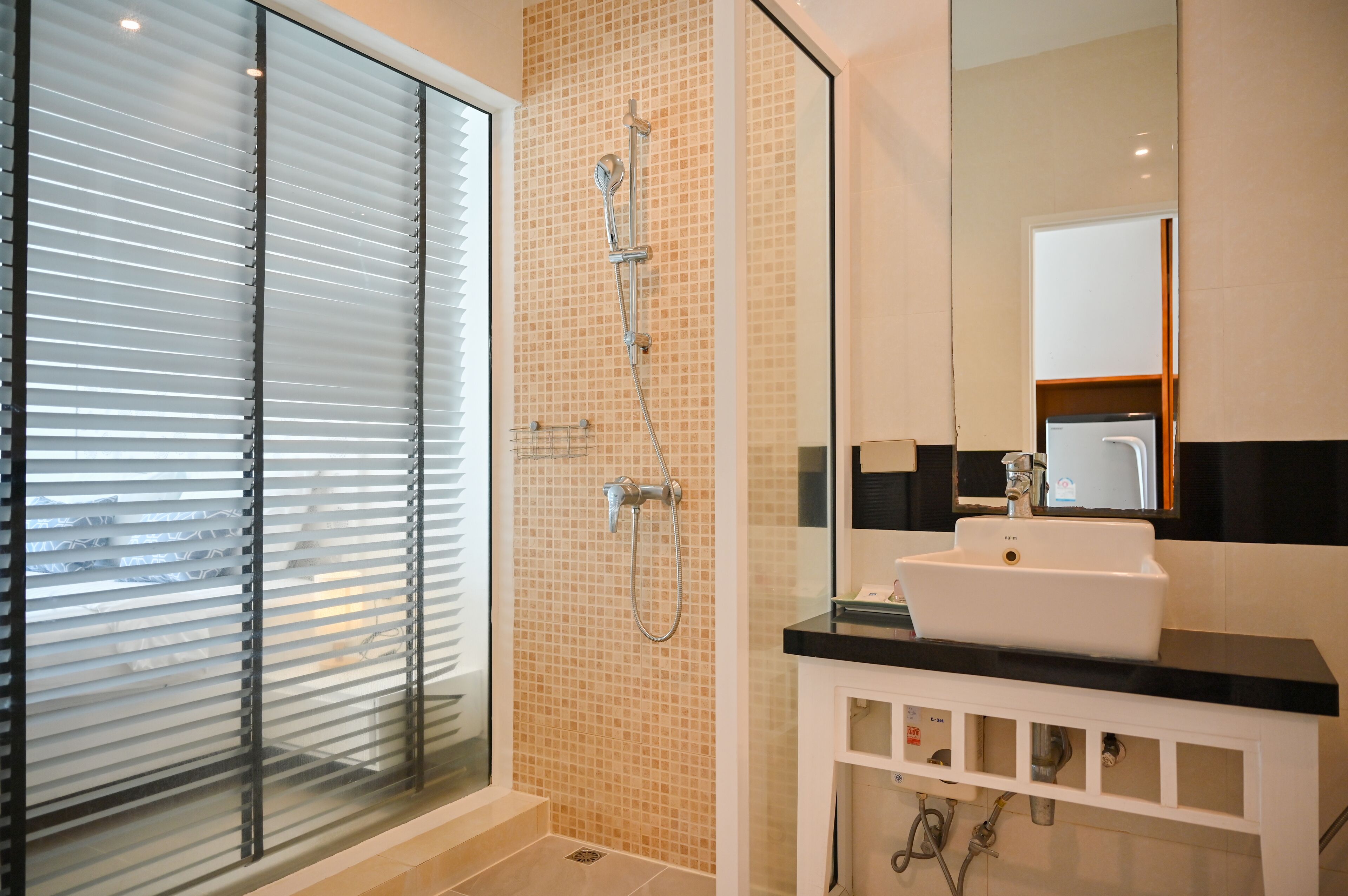 Une salle de bain moderne avec une douche à l’italienne en verre, un lavabo blanc et un miroir au-dessus.