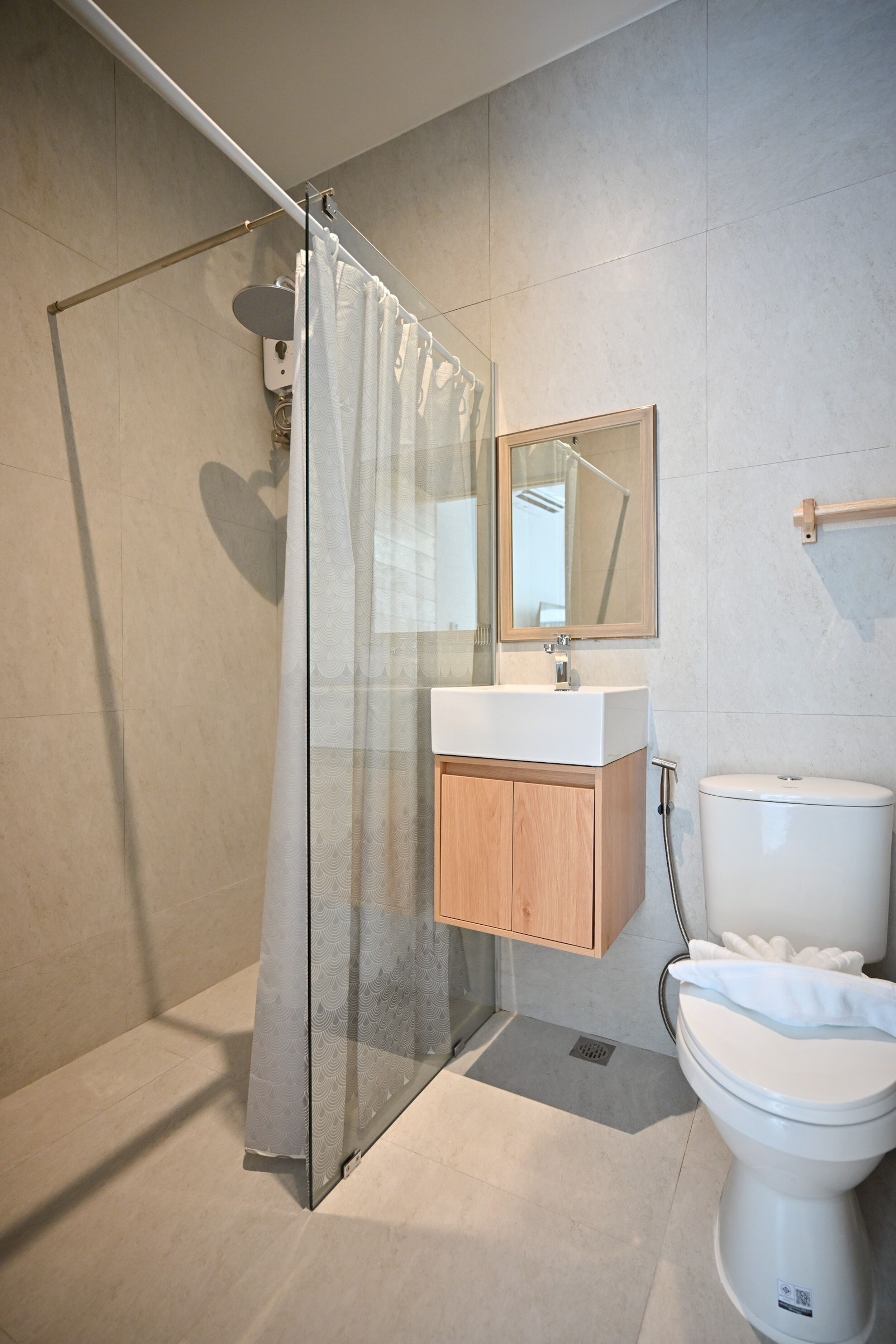 Ein modernes Badezimmer mit Duschkabine aus Glas, Waschtisch aus Holz, weißem Waschbecken und Toilette.