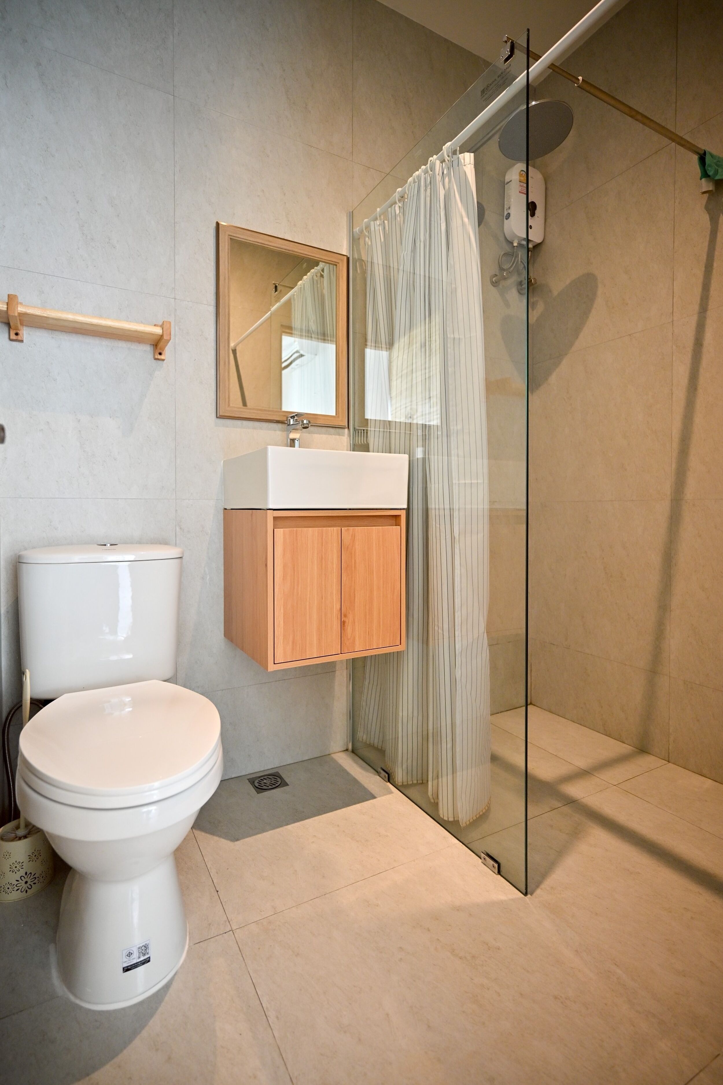 Un baño moderno con inodoro, un armario de madera, cabina de ducha de vidrio y un espejo.