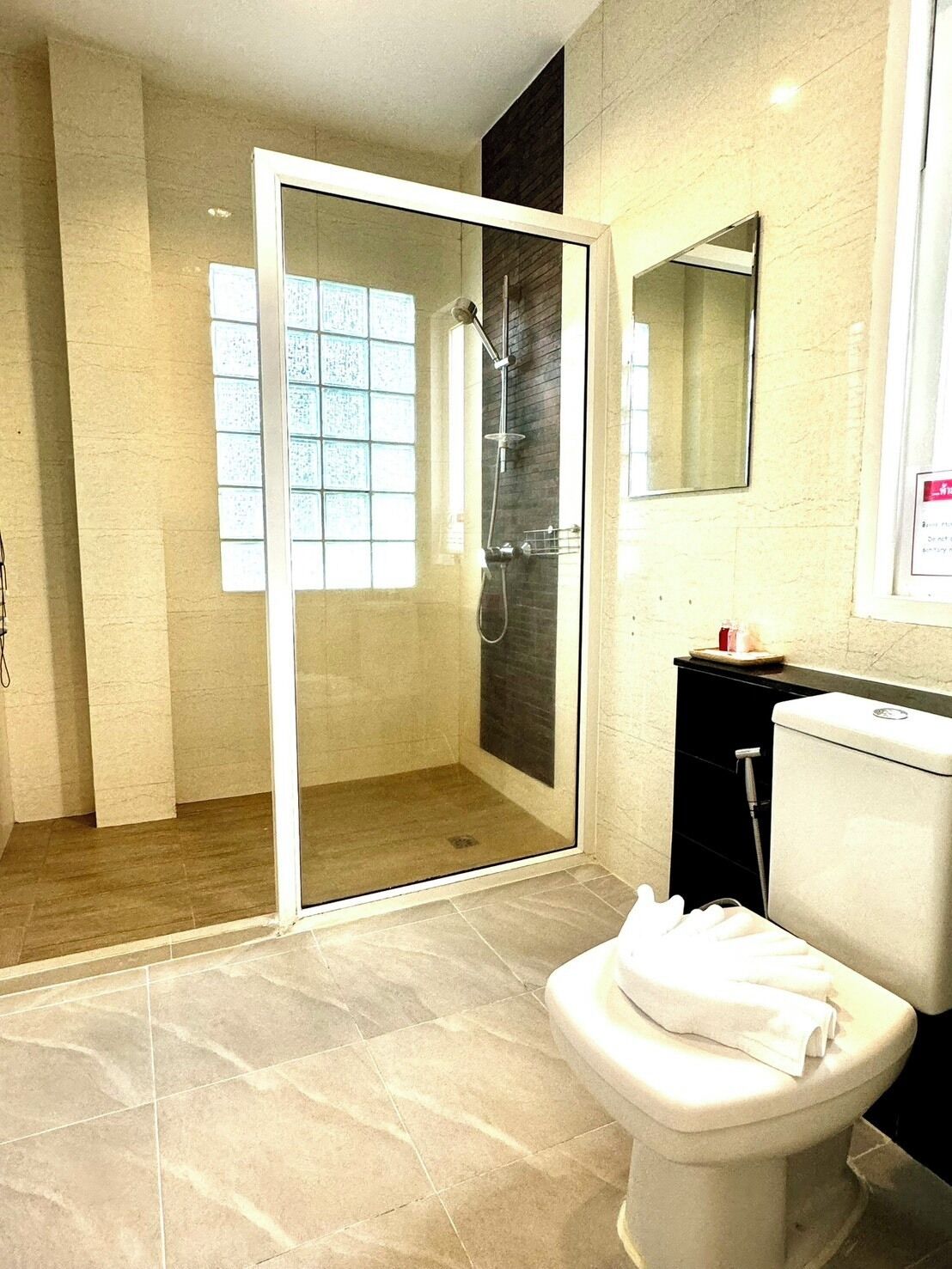Een moderne badkamer met een douchecabine van glas, een toilet en een wastafel met spiegel.