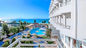 A hotel balcony with a pool view, including lounge chairs and umbrellas. - Lito Hotel (Rhodes)