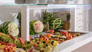 A buffet with various fruits and vegetables, including watermelon and pineapple, displayed on a glass counter. - Lito Hotel (Rhodes)